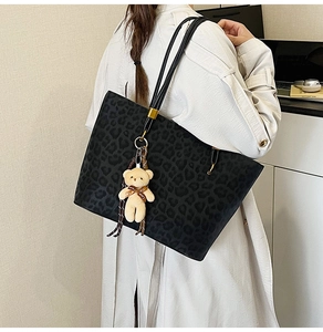 Detail of vintage leopard print tote bag with plush bear charm on a shoulder strap