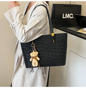 Detail of vintage leopard print tote bag with plush bear charm and black leather straps