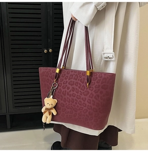 Close-up of wine red leopard print tote bag with soft texture and bear charm