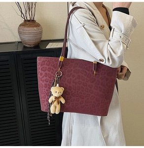 Detail of vintage leopard print tote bag with plush bear charm worn by a model