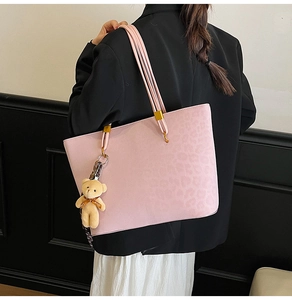 Pink faux leather leopard embossed tote bag with plush bear charm and gold hardware detail