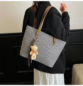 Detail of grey leopard print tote bag with brown rope handles and a cute bear charm