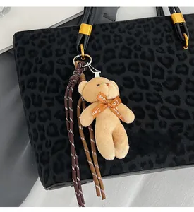 Detail of leopard print tote with golden buckle and plush bear charm accent