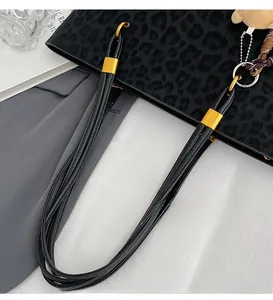 Detail of black leopard tote with woven long handles and golden metal buckles