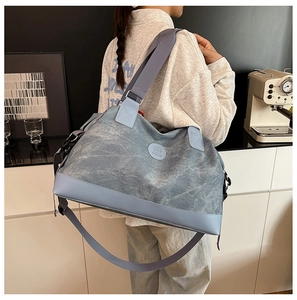 Detail view of large grey-blue canvas travel bag with durable straps and brand logo