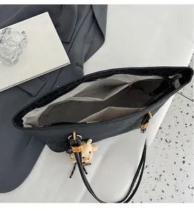 Interior view of black leopard tote bag with multiple pockets and plush bear charm