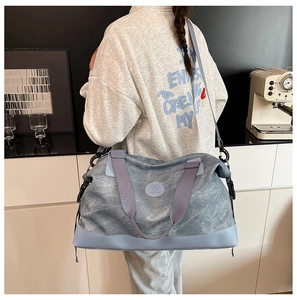 Detail of grey-blue canvas travel bag with leather base and adjustable shoulder strap