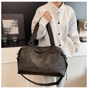 Detailed view of dark grey travel bag with circular logo and reinforced carry handles