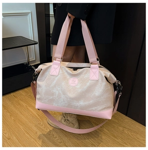 Detail of large capacity travel bag with pink shoulder strap and brand logo patch