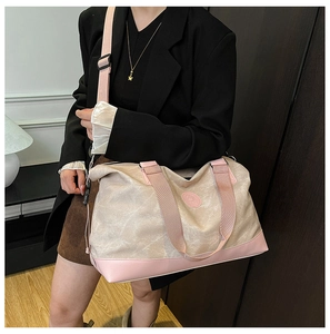 Detail of canvas travel bag featuring beige fabric with pink base and adjustable strap