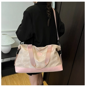 Rear view of a large cream and pink canvas travel bag worn by a model in a minimal setting