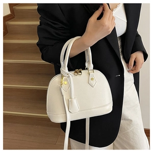 Borsa a conchiglia bianca in pelle martellata indossata su un blazer nero elegante