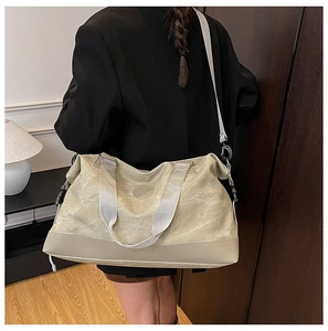 Detail view of beige canvas travel bag with thick reinforced base and shoulder strap
