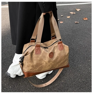 Detail of vintage canvas travel bag featuring brown leather trim and circular brand logo