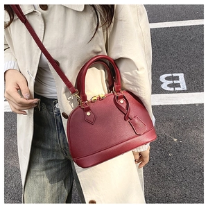 Dettaglio borsa a conchiglia rossa in pelle martellata con hardware dorato su modella