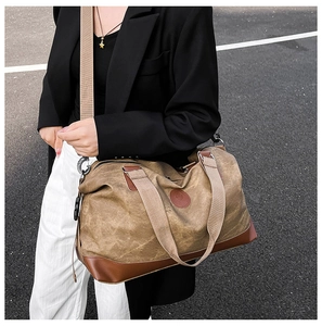 Detail of khaki canvas travel duffle bag with brown leather reinforcement and shoulder strap