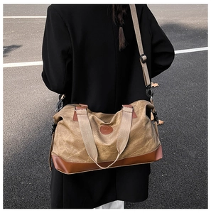 Street style view of large canvas travel bag with leather accents on male model