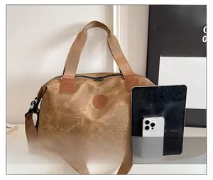 Close-up of canvas travel bag with leather trim, dual zippers and round brand logo