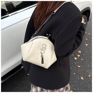 Sac bandoulière crème en cuir avec chaîne métallique et gland en situation extérieure