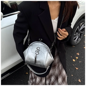 Détail du sac bandoulière argenté en forme de coquille avec chaîne et pompon élégant