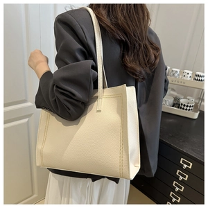 Detail of off-white lychee texture tote bag with brown stitching worn on shoulder