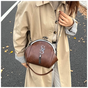 Détail du sac vintage marron avec fermoir métallique et élégant charme à pampilles