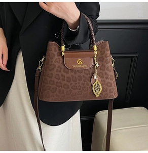 Détail du sac seau à motif léopard avec poignée tressée et pendentif feuille dorée
