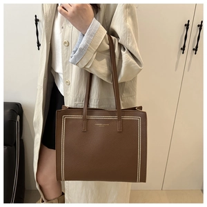 Dettaglio borsa tote in pelle marrone con cuciture bianche e stampa di tendenza