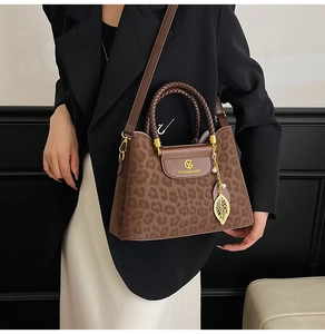 Détail du sac léopard avec poignée tressée et pendentif feuille en métal doré