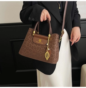 Détail du sac à main léopard avec poignées tressées et pendentif feuille dorée élégant