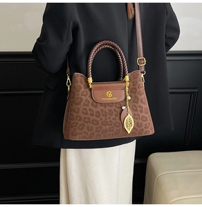 Détail du sac seau léopard avec poignée tressée et breloque en forme de feuille dorée