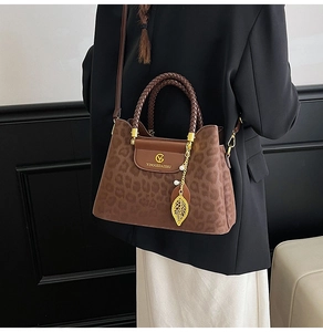 Détail du sac seau à motif léopard avec poignée tressée et pendentif feuille dorée