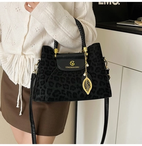 Détail du sac léopard avec logo doré, breloque en perle et poignée tissée élégante