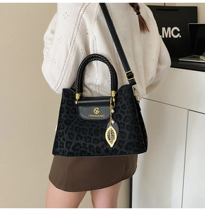 Détail latéral du sac léopard avec breloque feuille dorée et poignée tissée élégante
