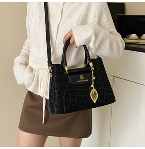 Gros plan du sac léopard avec pendentifs feuilles dorées et logo de la marque