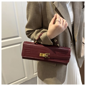 Detailed view of crocodile embossed leather texture and gold twist lock on burgundy bag
