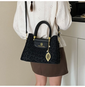 Détail du sac léopard avec breloque feuille dorée et poignée tressée chic