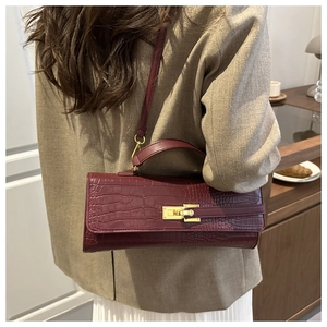 Woman wearing a wine red crocodile pattern handbag with gold lock in a cafe