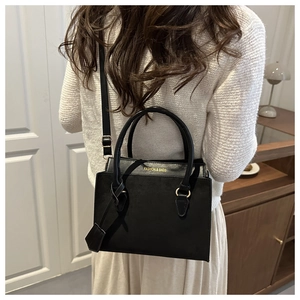 Detail of a black matte tote bag with gold lettering and adjustable shoulder strap