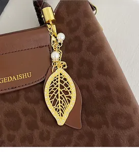 Pendentif feuille dorée avec perles et cristaux sur sac seau motif léopard élégant
