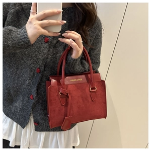 Detail of burgundy tote bag showing suede texture, leather handles, and fashion lettering