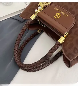 Détail de la poignée en cuir marron tressé avec ferrures métalliques dorées sur un sac seau