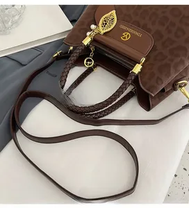 Détail du sac seau léopard avec pendentif feuille dorée et poignée supérieure tressée