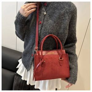 Detail view of red suede leather crossbody bag with gold buckle and fashion text
