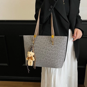 Fashionable grey leopard print tote bag with brown handles and a cute bear pendant charm