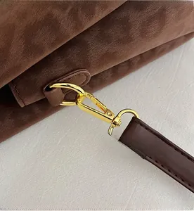 Détail du fermoir en métal doré et de la bandoulière en daim marron du sac seau chic