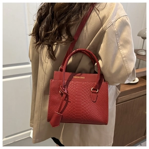 Detail of red snake-patterned handbag with round handles on a khaki trench coat