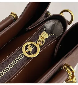 Détail de la fermeture éclair dorée avec motif kangourou sur sac en cuir marron