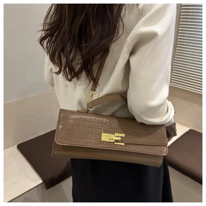 Detailed view of crocodile pattern crossbody bag with golden clasp and leather strap