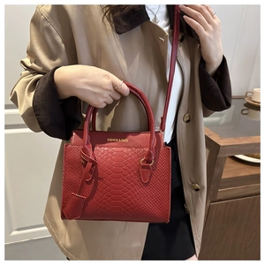 Detail of red snake pattern handbag featuring a fashion logo and leather texture